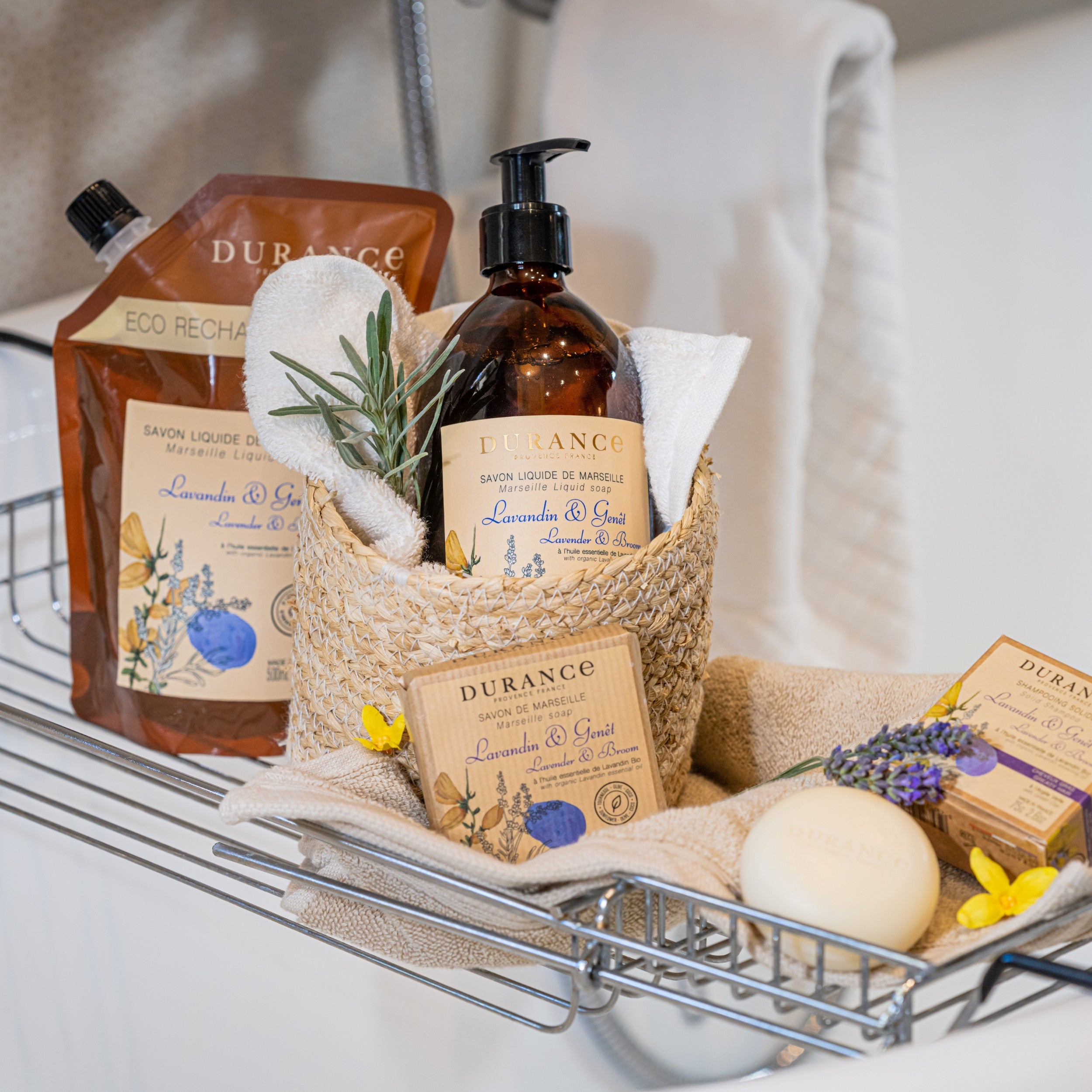 Bath caddy with Durance soap, liquid soap, and other products on a bathtub rack.