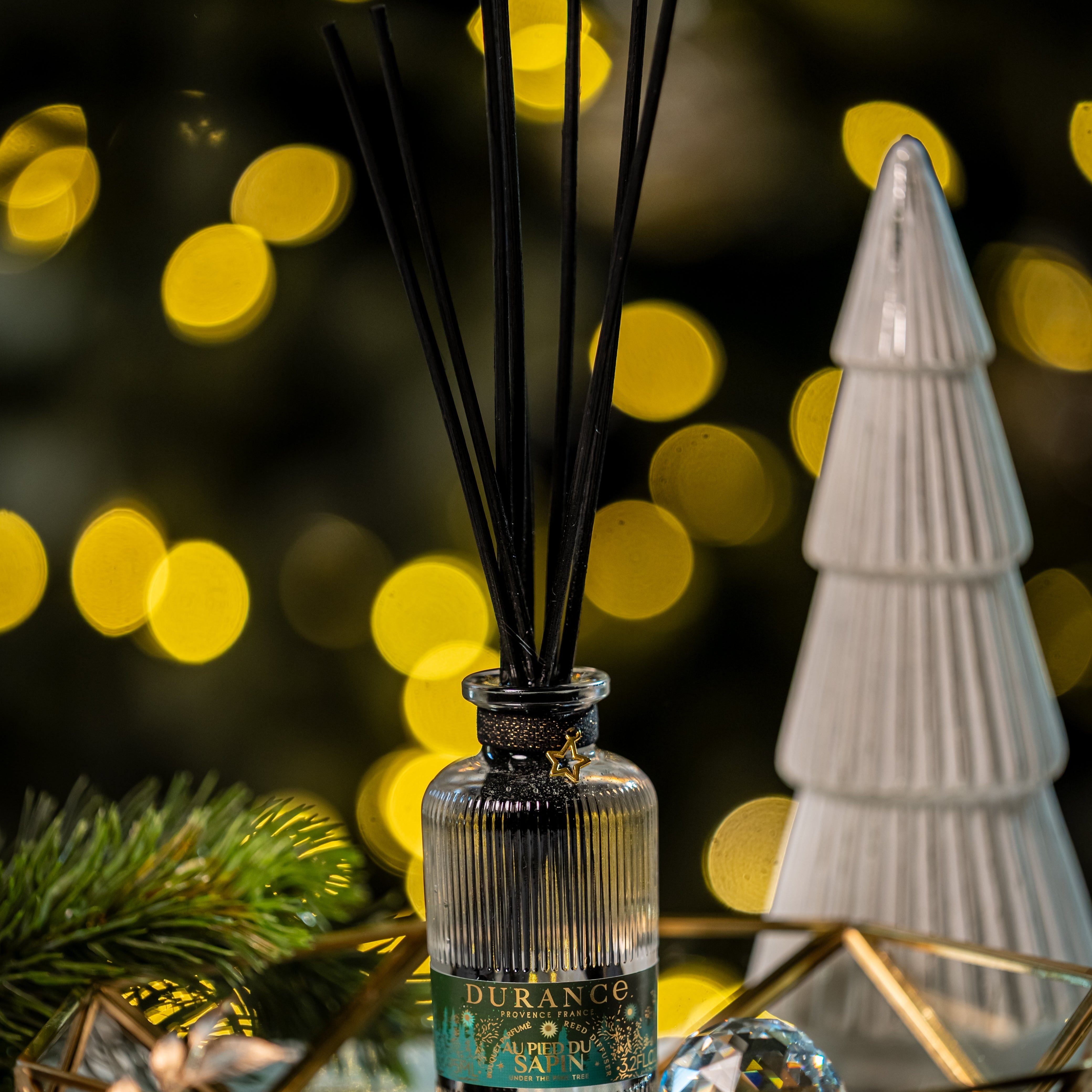 Diffuser with black sticks on a decorative tray with blurred lights in the background