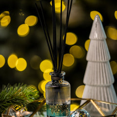 Diffuser with black sticks on a decorative tray with blurred lights in the background