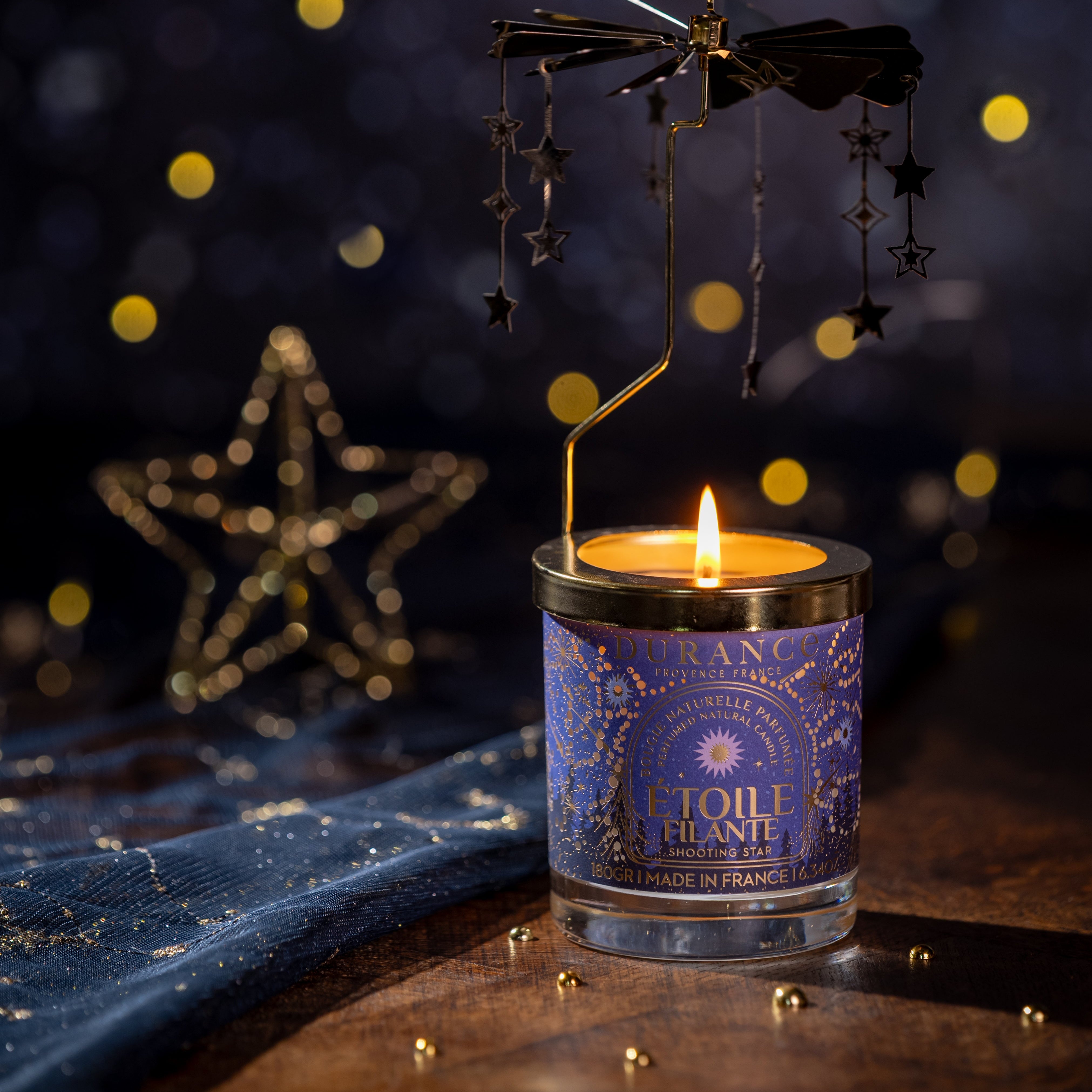 Candle in a decorative container with starry design on a dark background