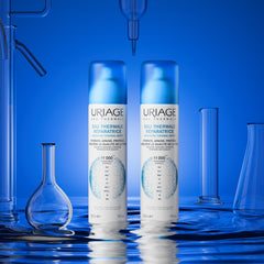 Two Uriage bottles with a blue background and laboratory equipment.