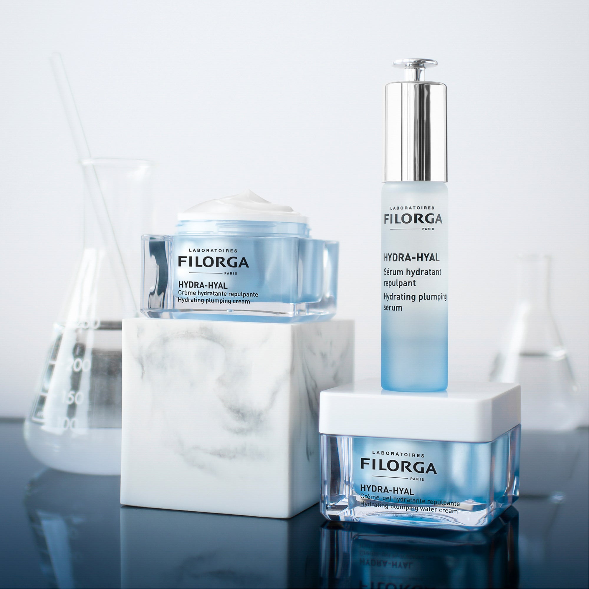 Filorga skincare products including a serum, cream, and plumping cream on a reflective surface with a light background.