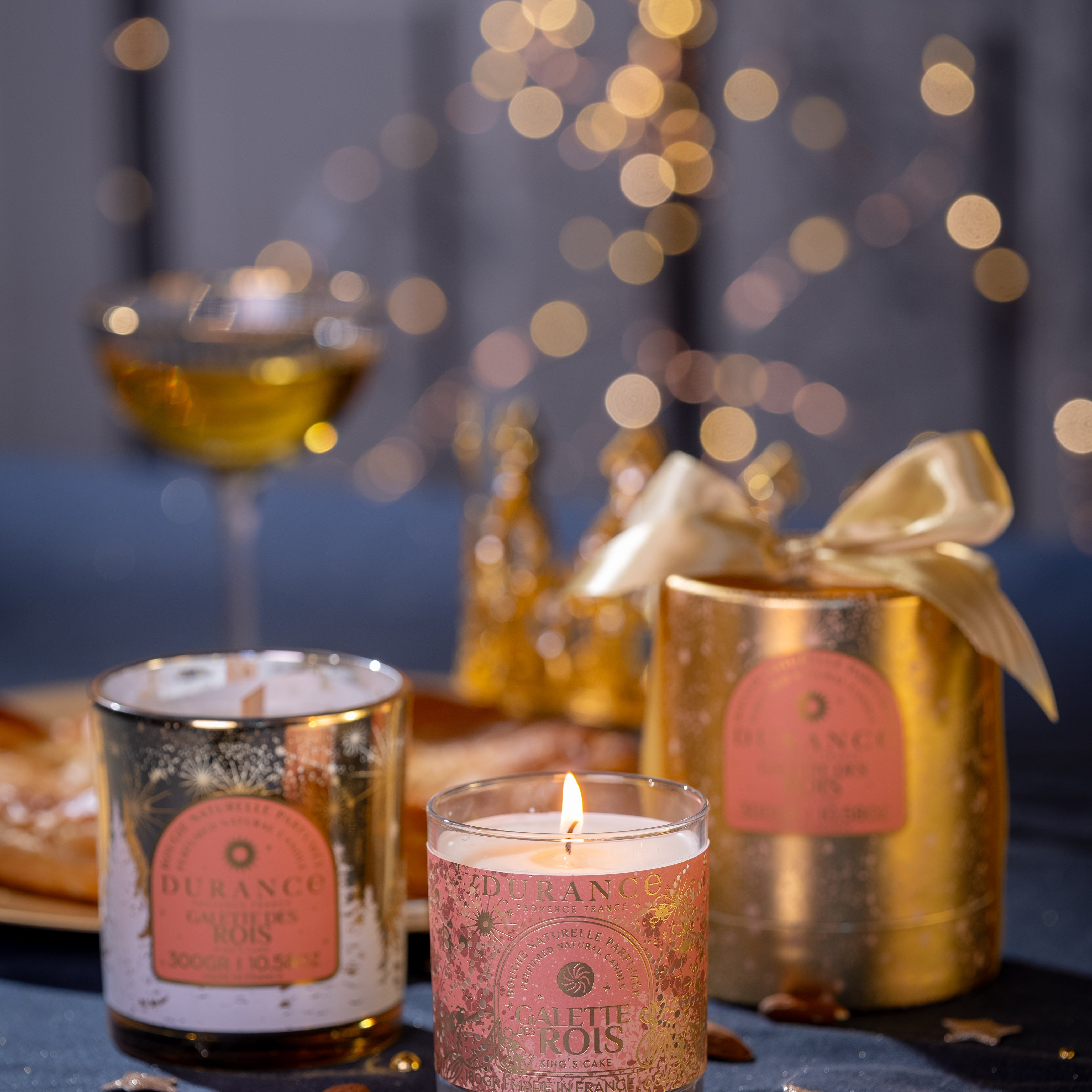Candle with decorative label on a table with blurred lights in the background