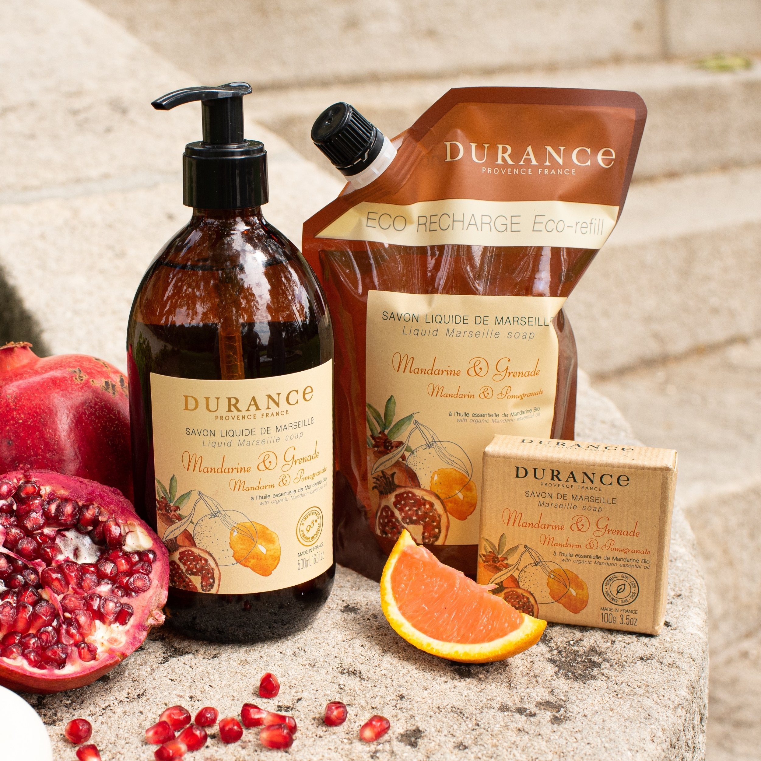Durance soap products including a bottle, pouch, and bar on a stone surface with pomegranate and grapefruit.