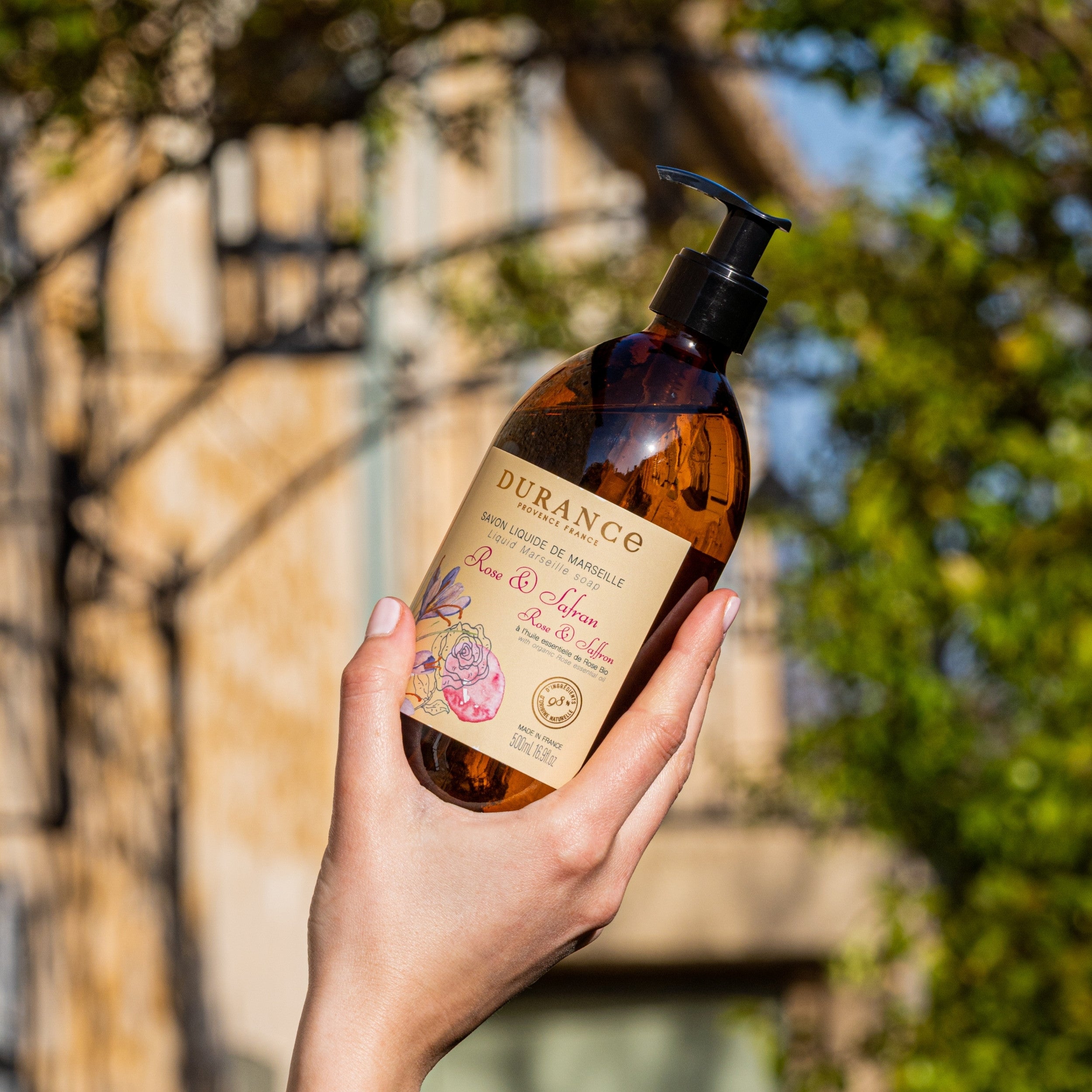Hand holding a Durance soap bottle with a blurred outdoor background