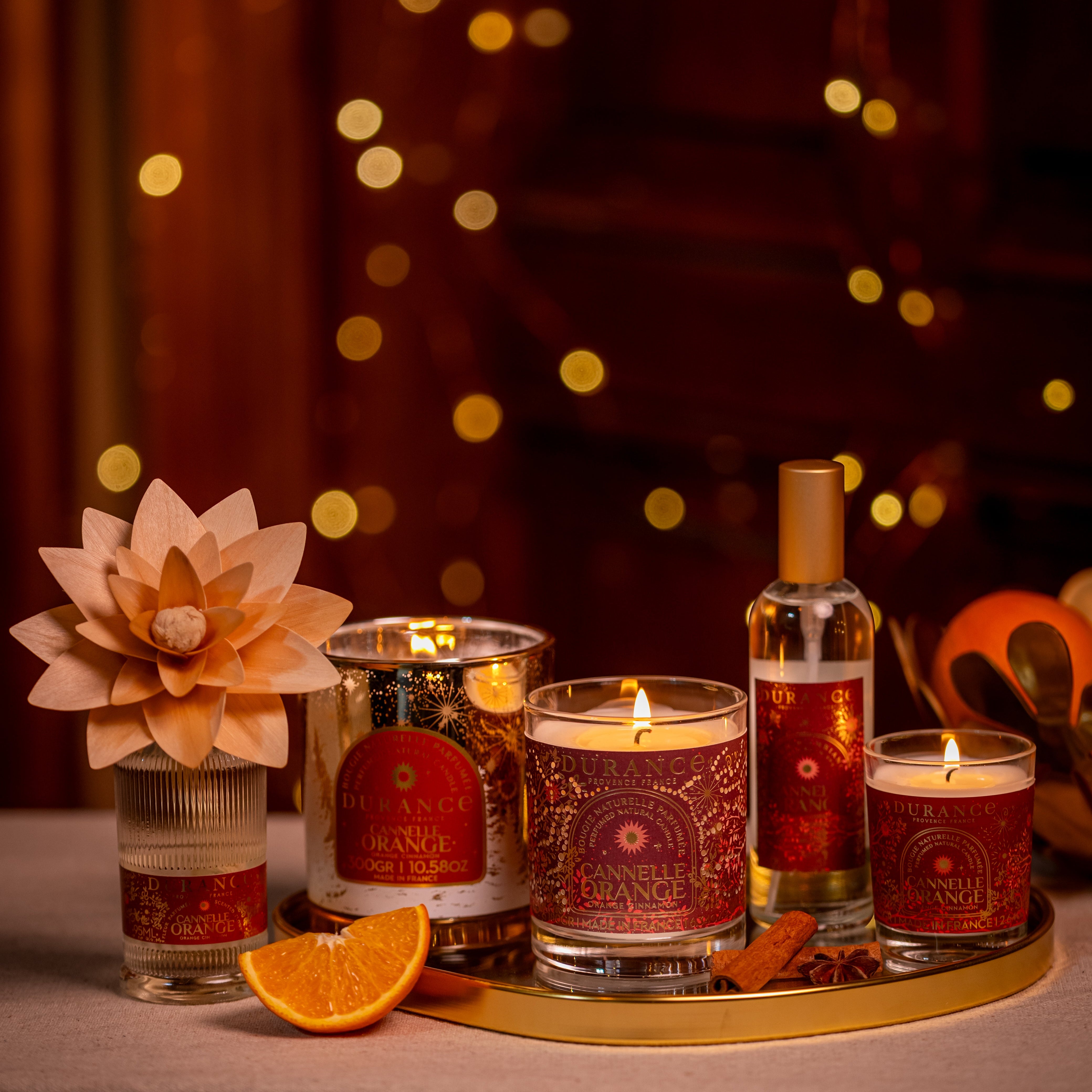 Decorative candles and bottles on a tray with a warm, blurred background