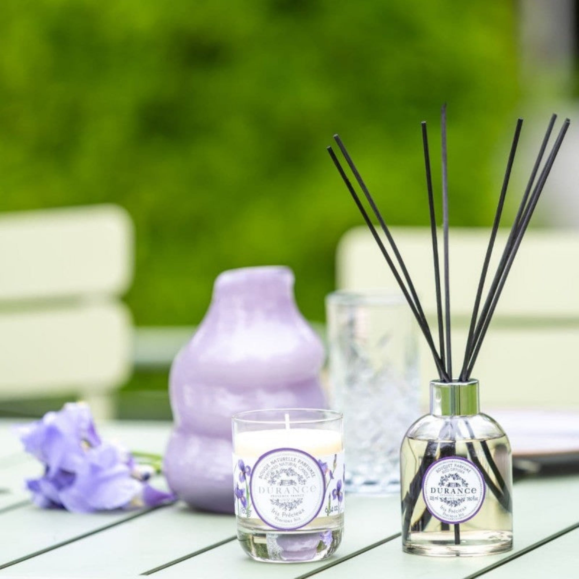 Decorative items including a candle, diffuser, and vase on a table outdoors.