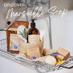 Bath caddy with Marseille soap products including bottles, bars, and a towel on a white background.