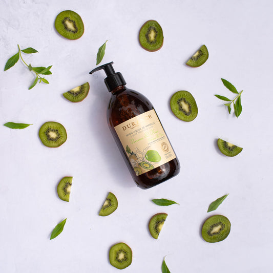 Brown bottle with a label on a white background surrounded by sliced kiwis and leaves