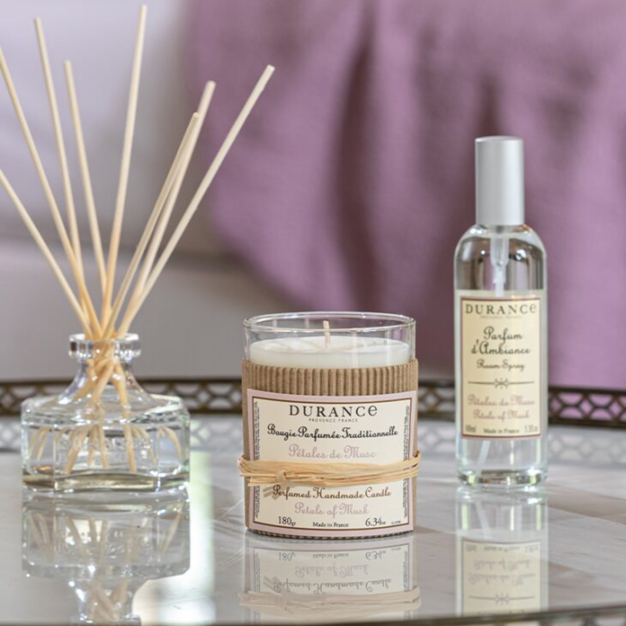Durance candle, diffuser, and room spray on a reflective surface with a blurred background