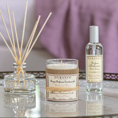 Durance candle, diffuser, and room spray on a reflective surface with a blurred background