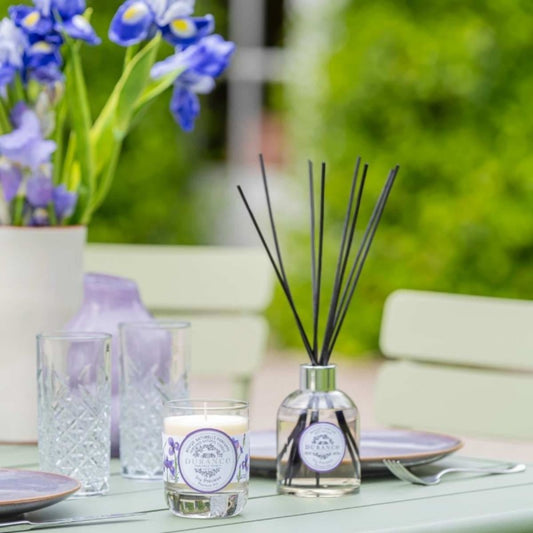 Table setting with a diffuser, candle, and flowers on a blurred outdoor background