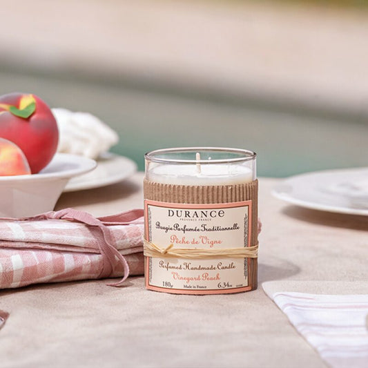 Durance candle on a table with peaches and a checkered cloth in the background