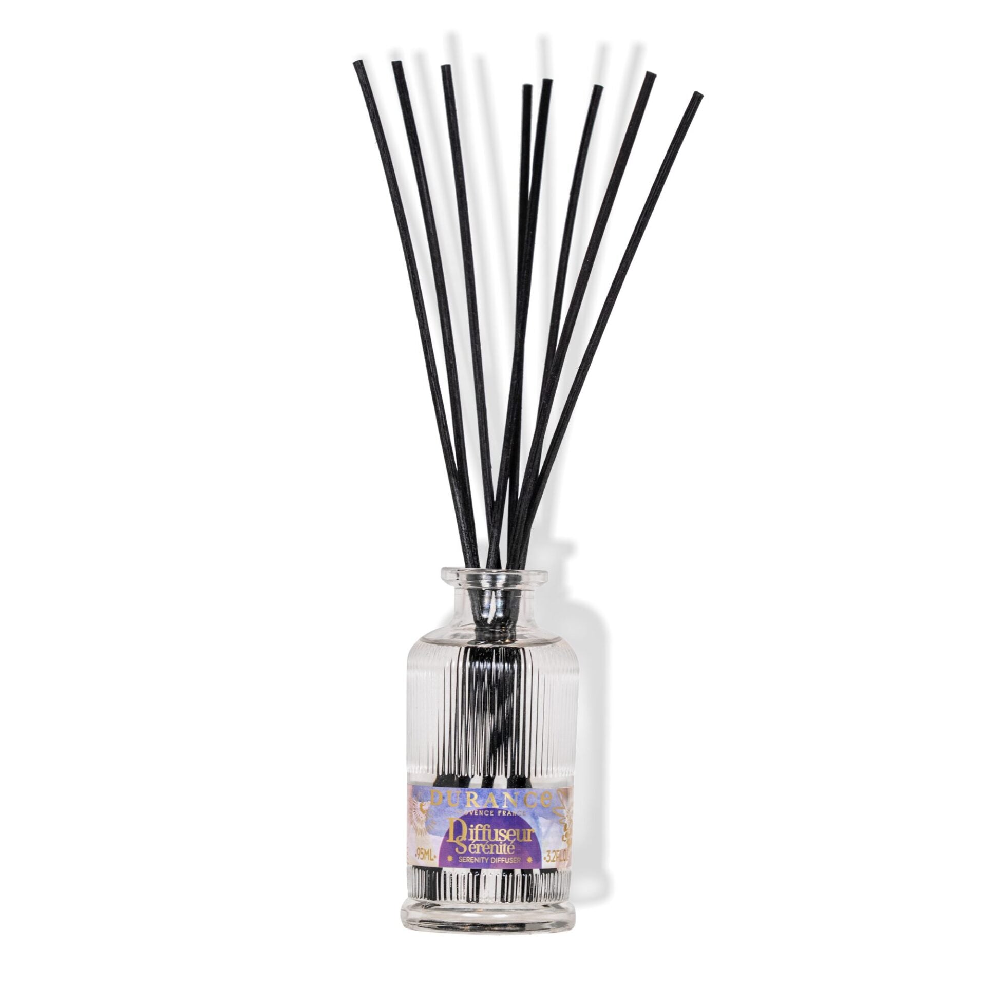 Reed diffuser with black sticks in a clear bottle on a white background