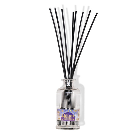 Reed diffuser with black sticks in a clear bottle on a white background