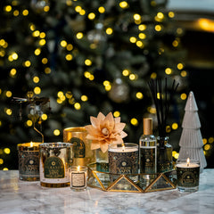 Decorative candles and diffusers on a table with a Christmas tree in the background