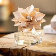 Perfume bottle with decorative flower on a wooden surface