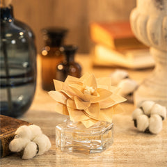 Decorative flower in a glass vase on a wooden surface with blurred background